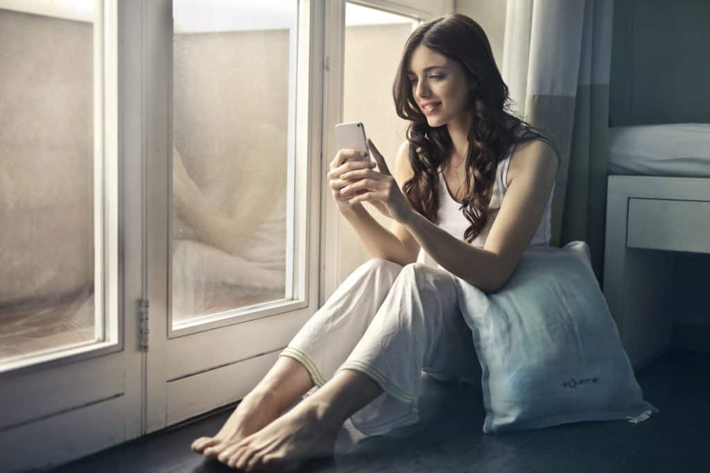 A girl confidently using her phone from her bedroom