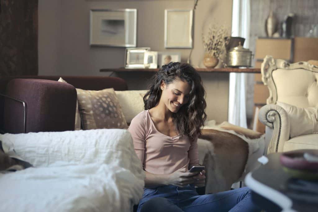 A woman smiling at her phone at home