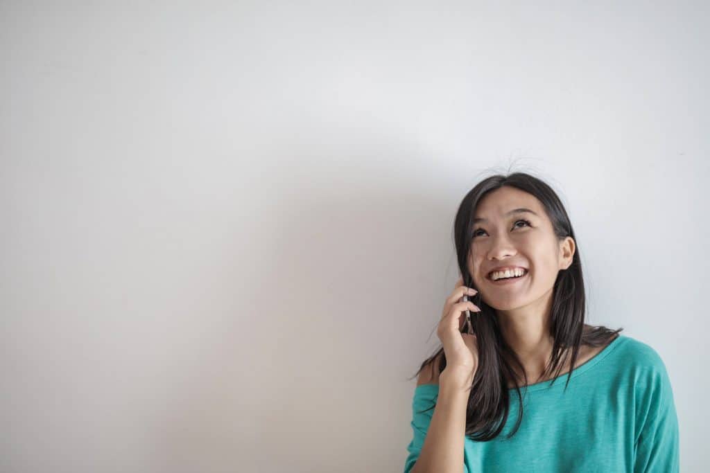 An Asian woman on the phone with a smile on her face