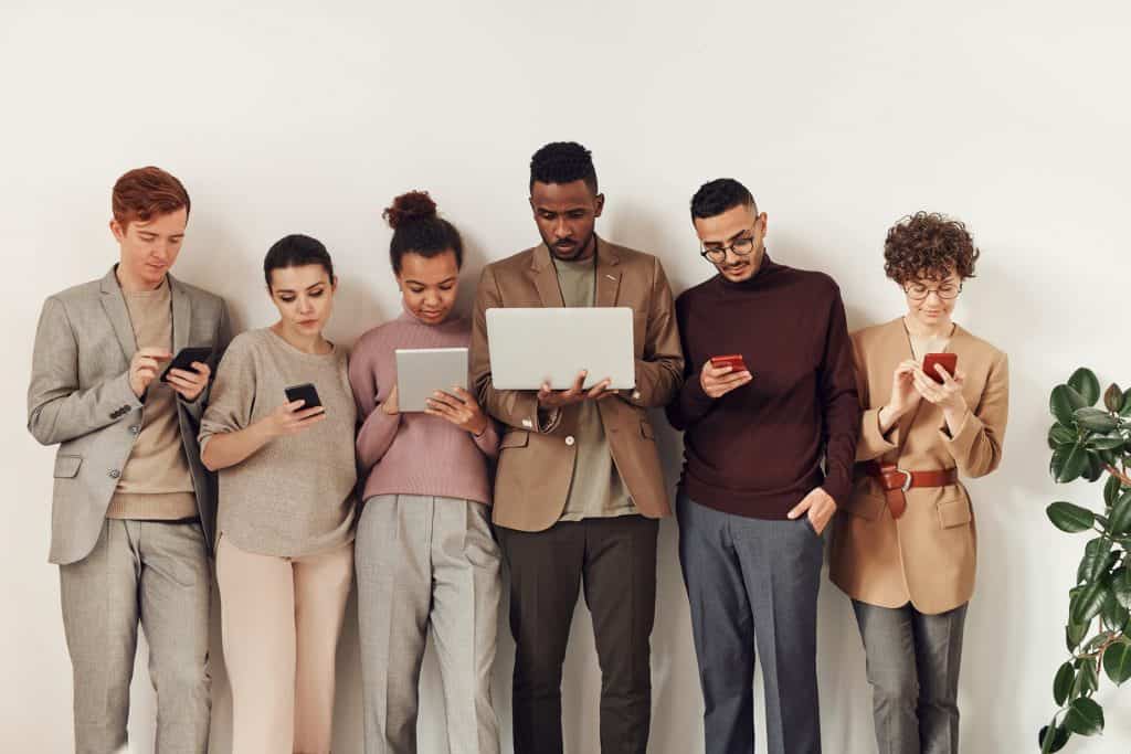 A group of people holding their phones and laptops