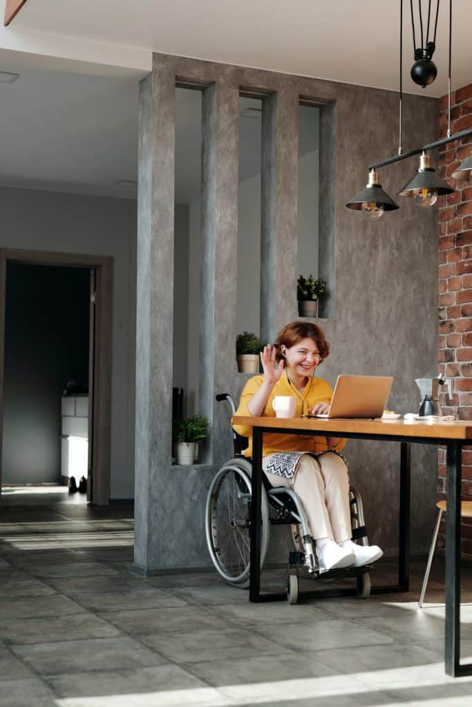 A woman in a wheelchair in front of her desk on the phone