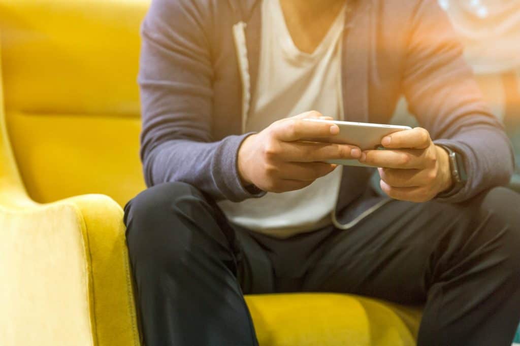 A man holding a phone and sitting on a yellow sofa