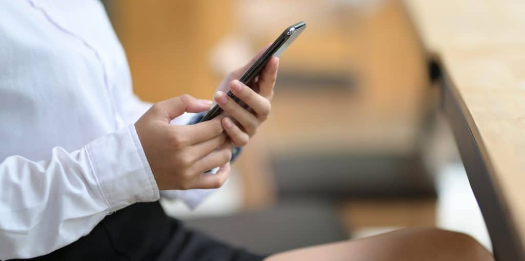 A woman holding her phone and looking down at it