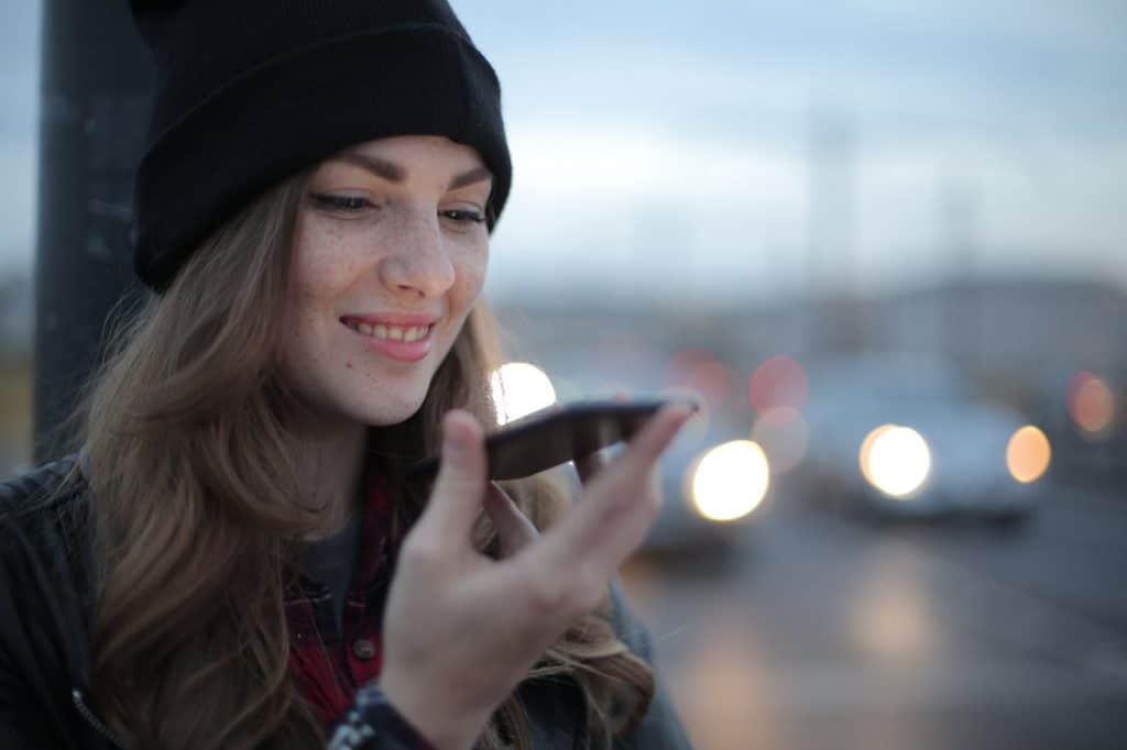 A girl holding her phone on the side of the road