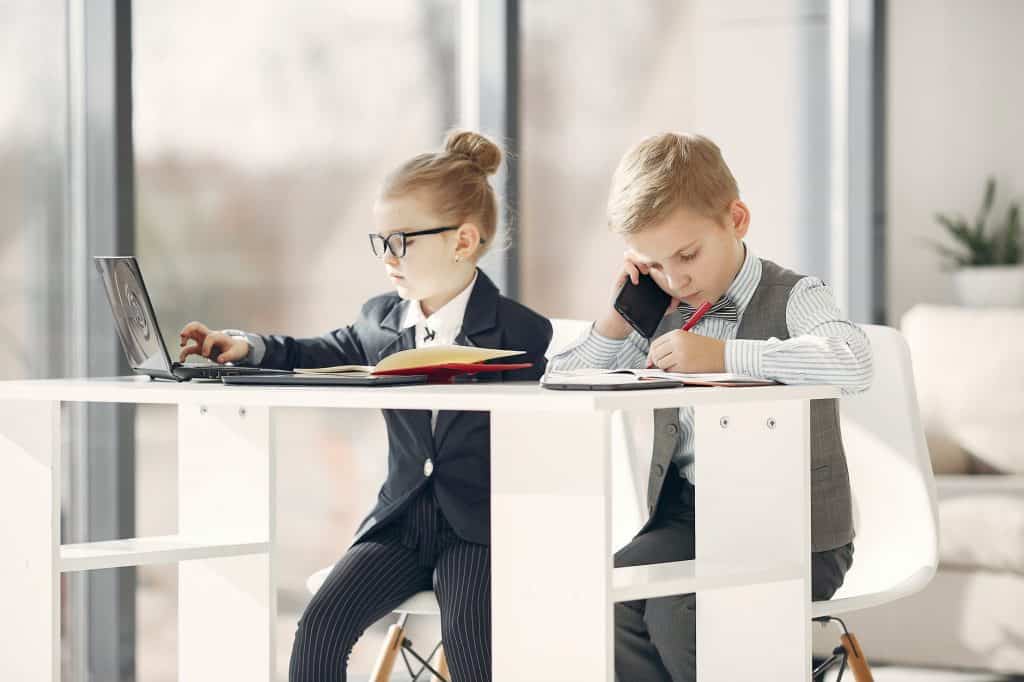 Two young children on the phone dressed as businessmen