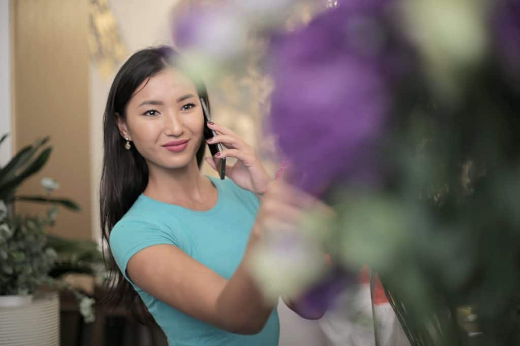 An Asian woman on the phone and looking at flowers