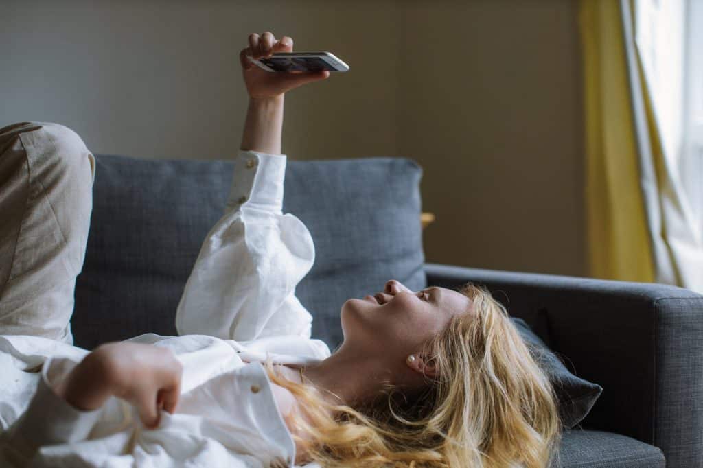 A girl lying on the sofa holding her phone up