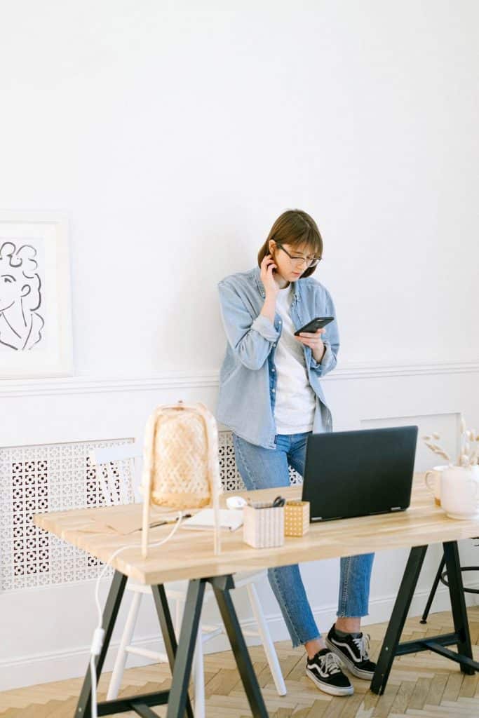 A girl looking down at her phone in front of her desk