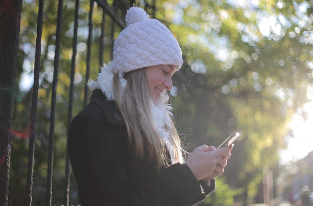 A woman in a white winter hat looking down at her phone