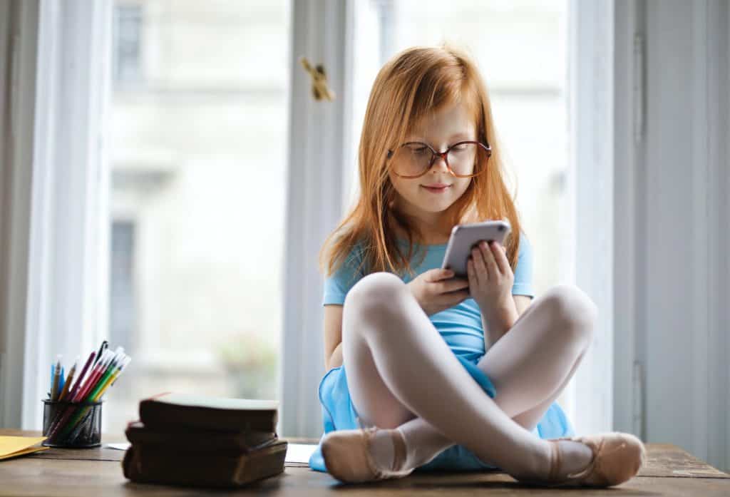 A little girl with red hair playing with her phone