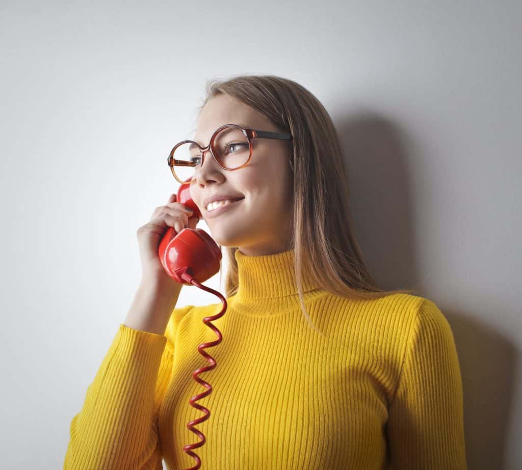 A woman in a yellow sweater holding a red phone