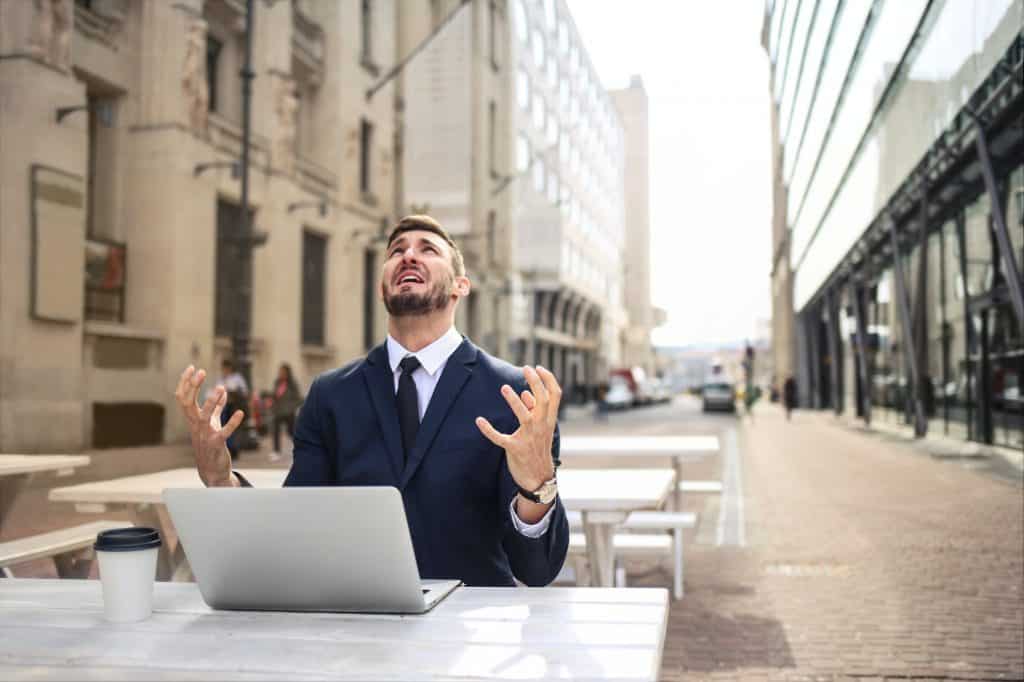 A distressed businessman with his laptop on an outside table  