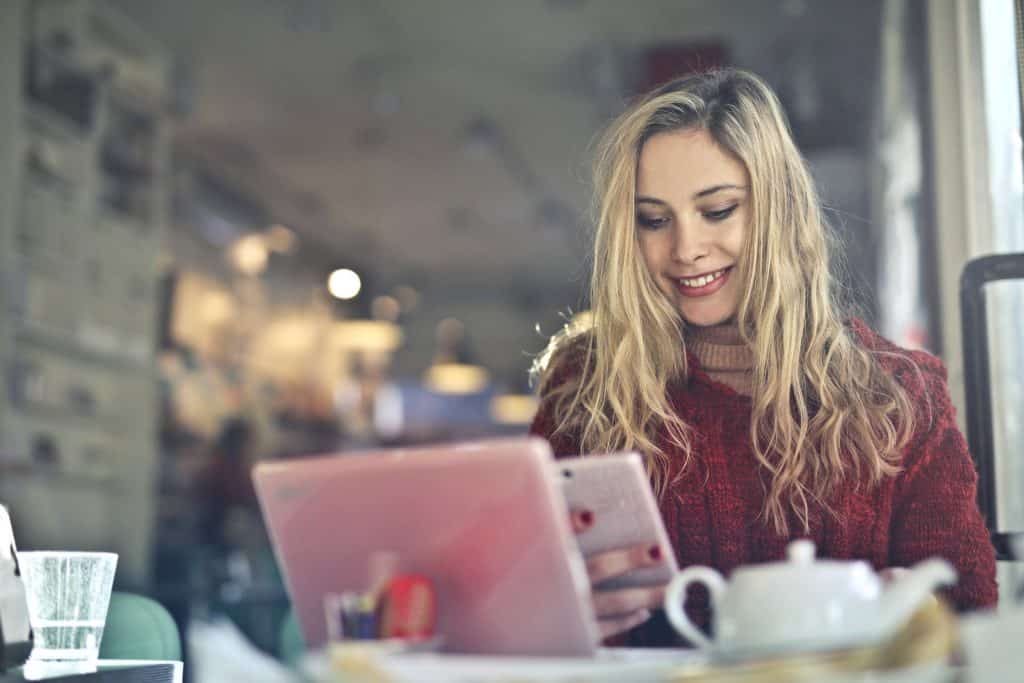 A blonde woman in a red sweater looking at her phone