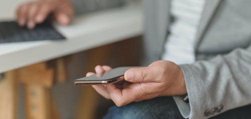 A man in a suit sitting and holding a phone