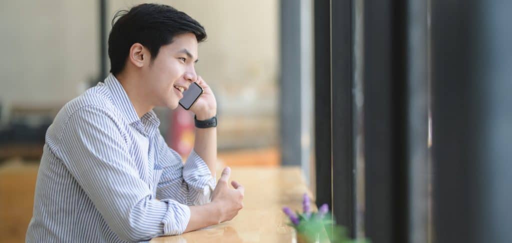 A man sitting at a desk and speaking on the phone