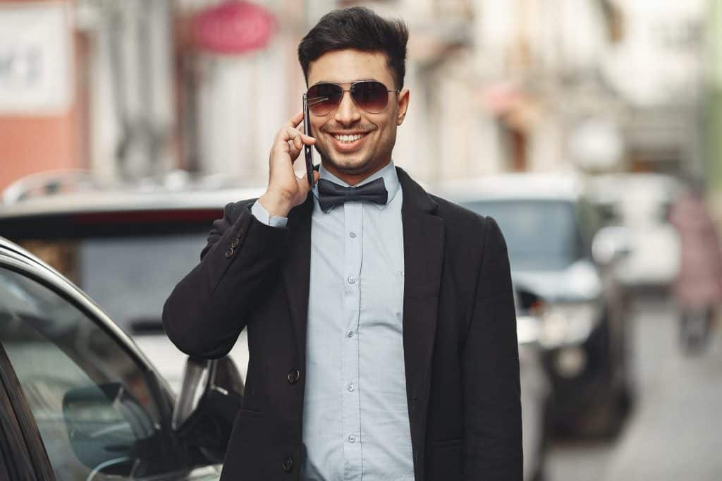 A man wearing a suit and sunglasses as he talks on the phone