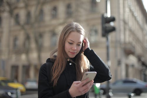 A woman in a black coat looking down at her down