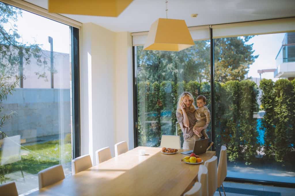 A mother holding her son in the kitchen while talking on the phone