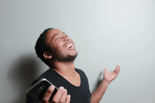 A man laughing as he holds his phone