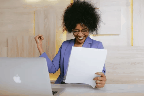 A woman smiling as she holds a paper