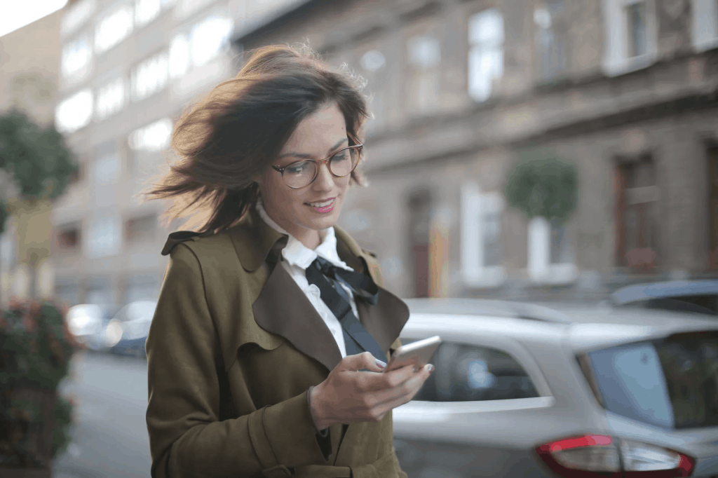 A woman wearing a coat and holding her phone