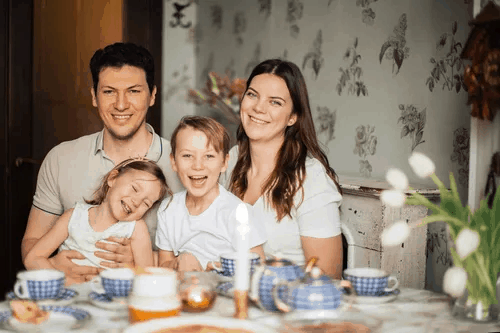 A laughing smiling happy family of four sitting at the dinner table 