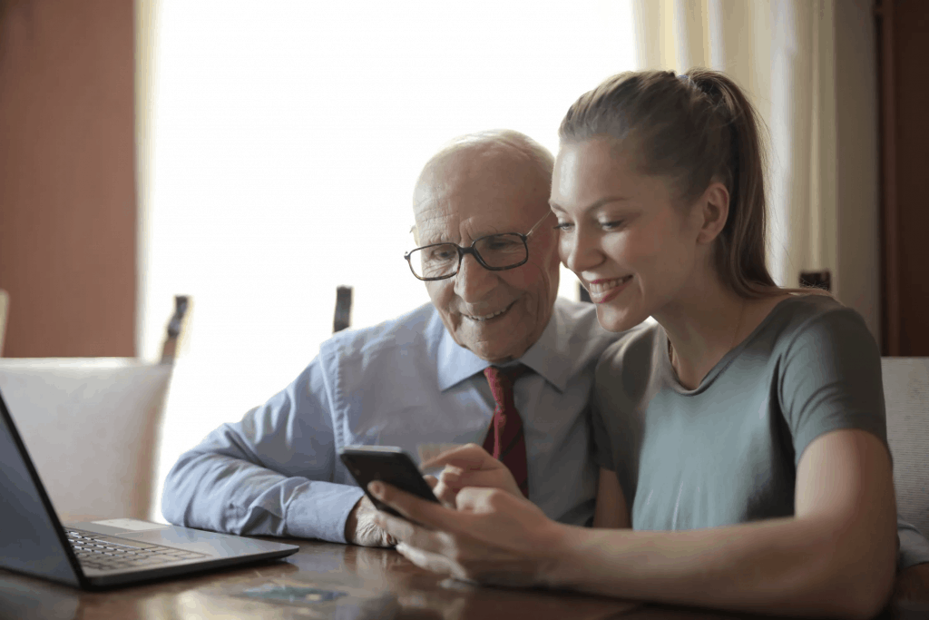 A young woman showing her father how to use a smartphone