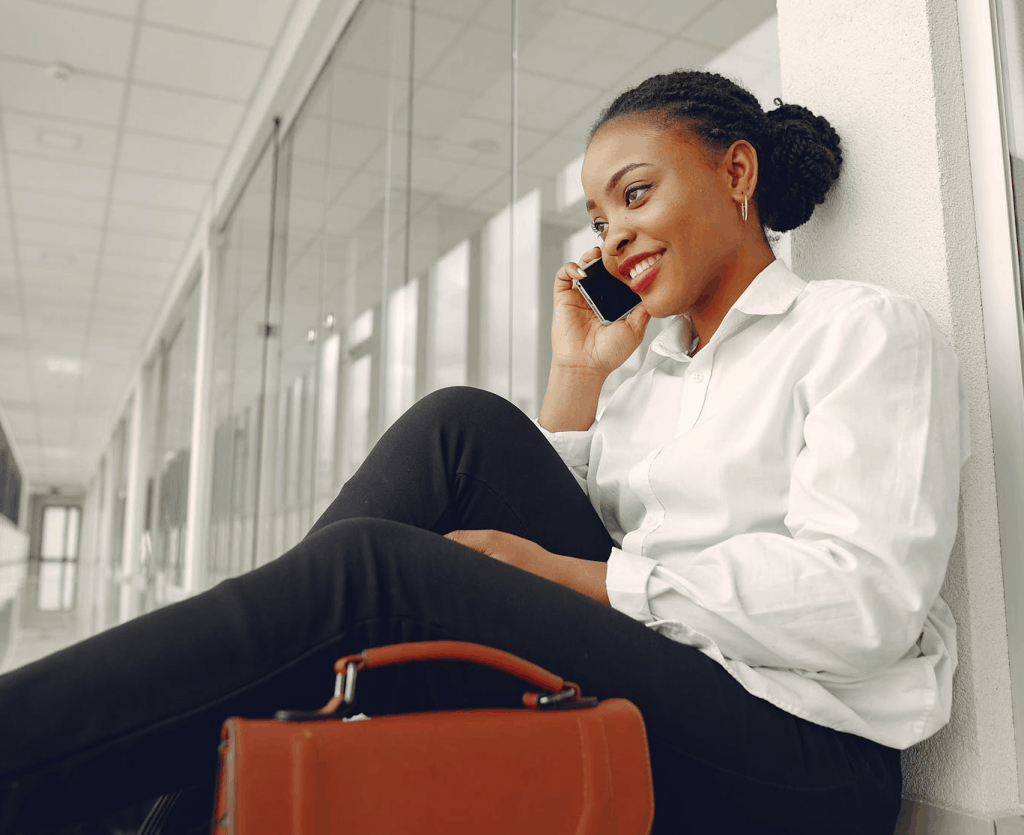 A woman sitting on the floor of a modern office speaking on the phone 