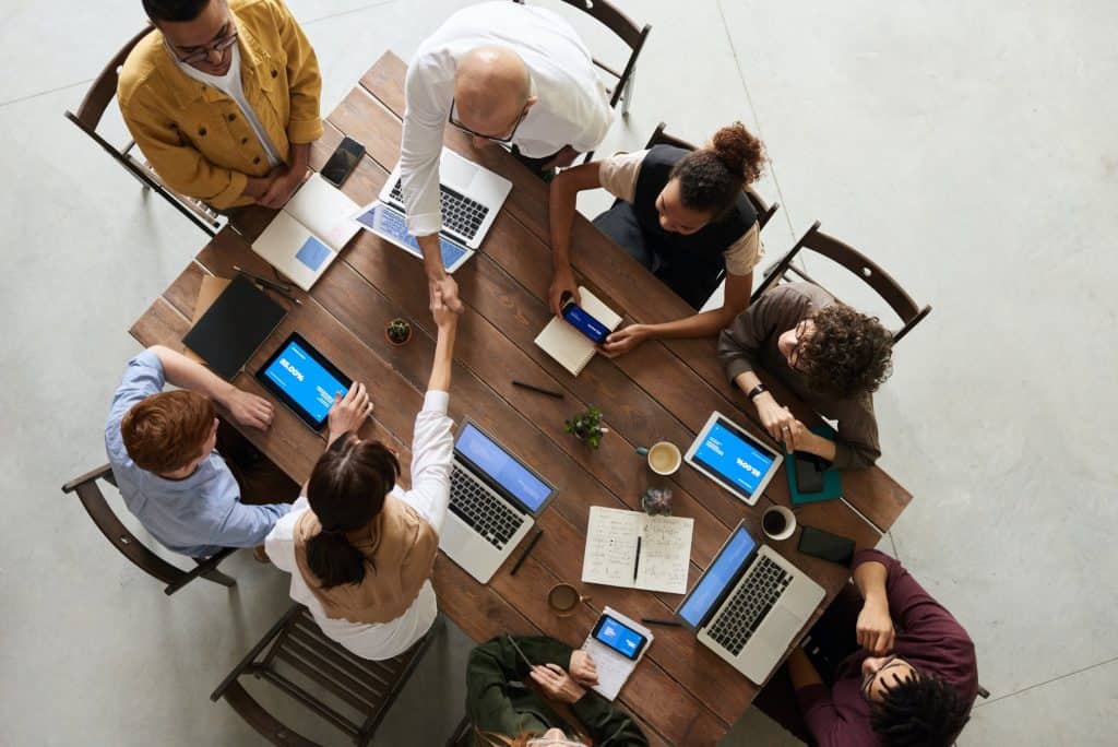 A group of people working together at a table and shaking hands 