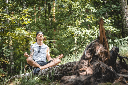 A man meditating next to a tree log 