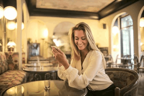 A blonde woman in a white shirt holding a phone