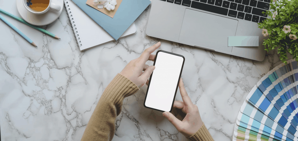 A blank phone screen being held on a marble desk