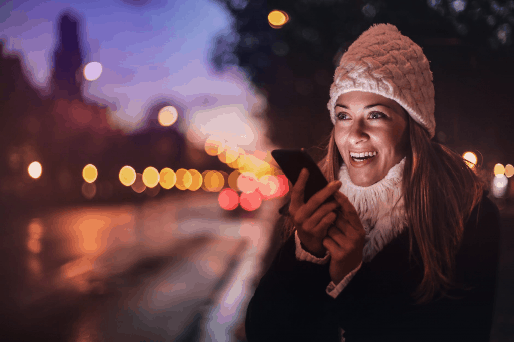 A woman wearing a white winter hat holding her phone