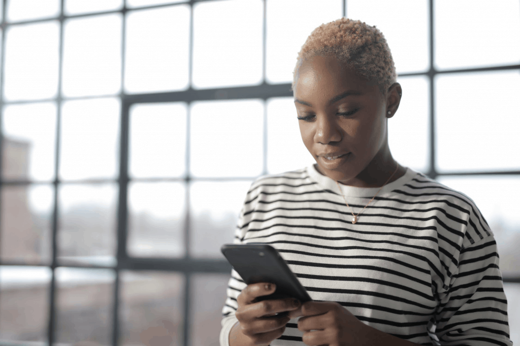 A woman in a stripped shirt holding her phone