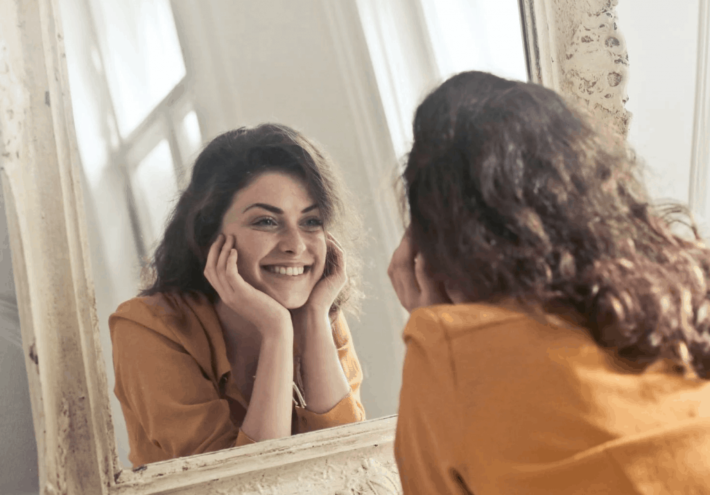 A young woman smiling at herself in the mirror 