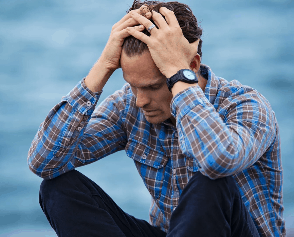 A stressed out man holding his head