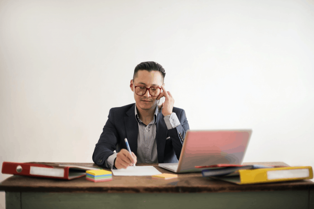 A man speaking on the phone while sitting at his desk