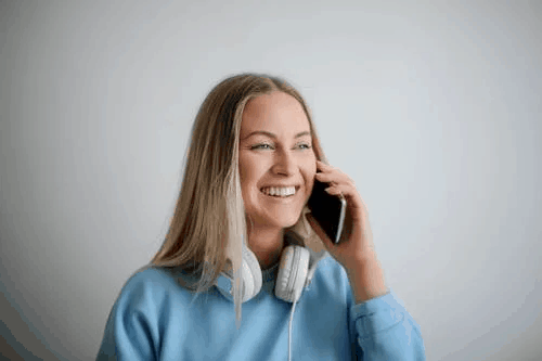 A blonde woman in a blue sweater speaking on the phone