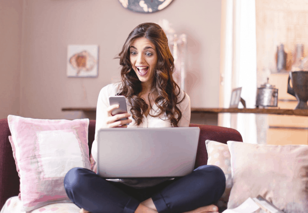 A very happy woman holding her phone on the sofa