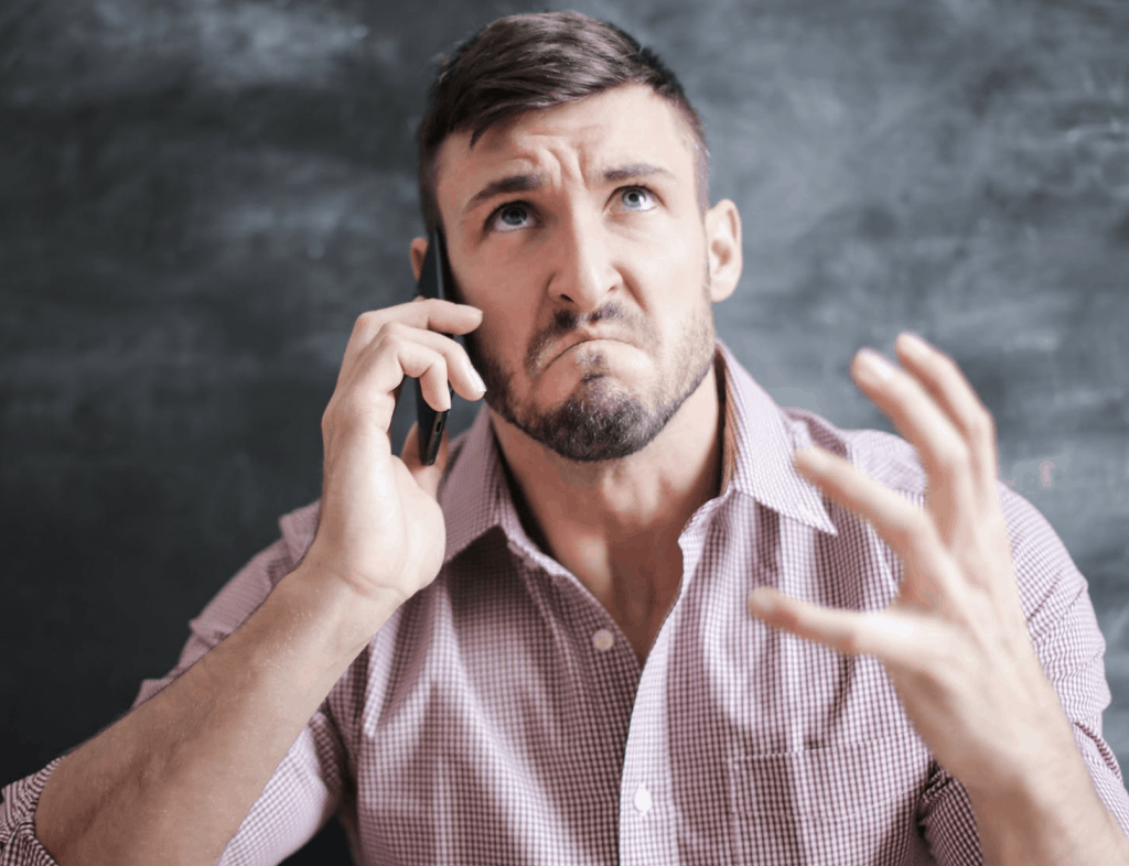 A man in a pink dress shirt angry on the phone