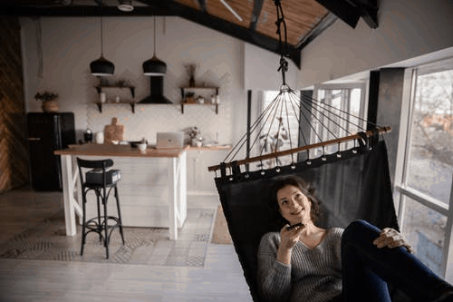 A woman laying down in a hammock while speaking on the phone