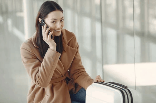 A woman in a beige coat speaking on the phone 