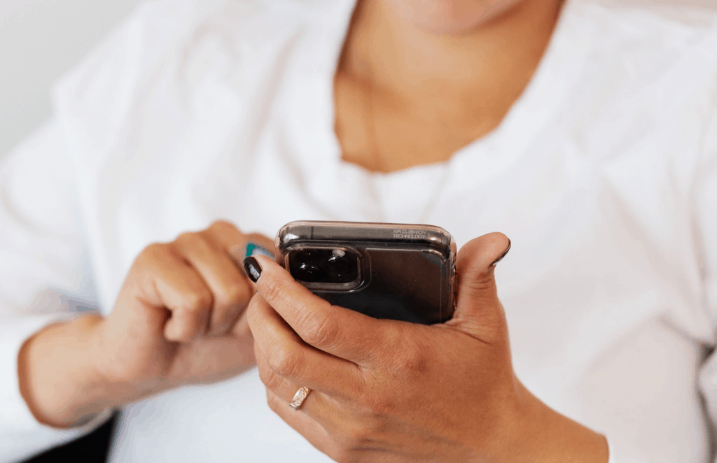 A woman in a white shirt holding her smartphone 