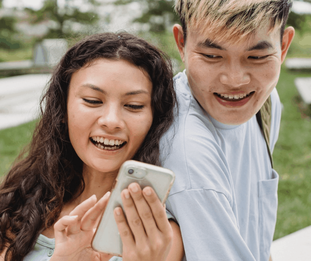 An Asian couple smiling while looking at a phone screen