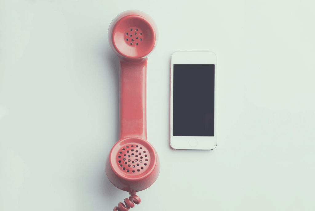 A red home phone next to a white mobile phone