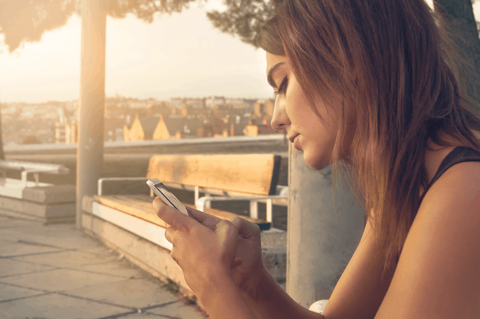 A woman holding her phone in front of blurred nature view