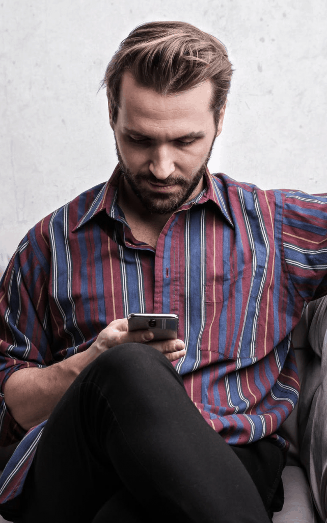 A man in a stripped shirt looking at his phone