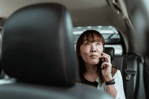 An Asian woman speaking on the phone while sitting in the car