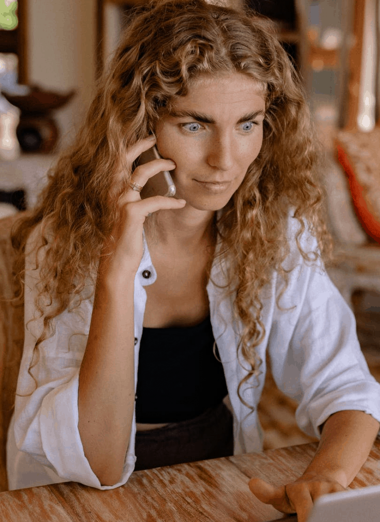 A blonde curly hair woman looking shocked on the phone