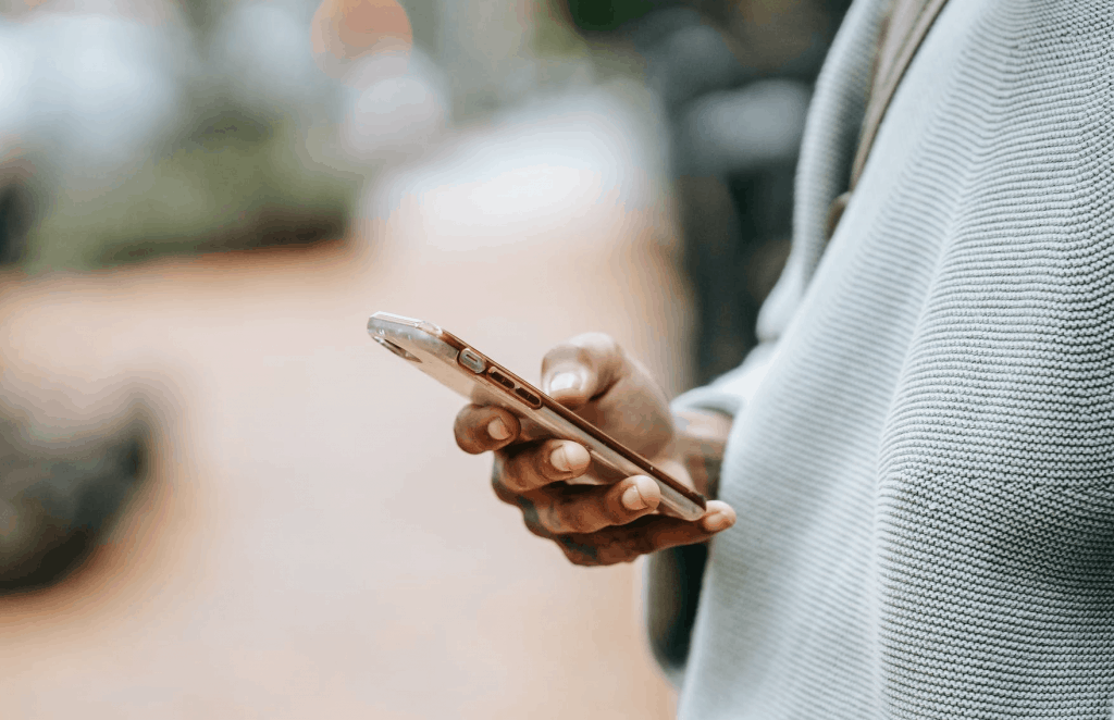 A man in a grey sweater holding a smartphone